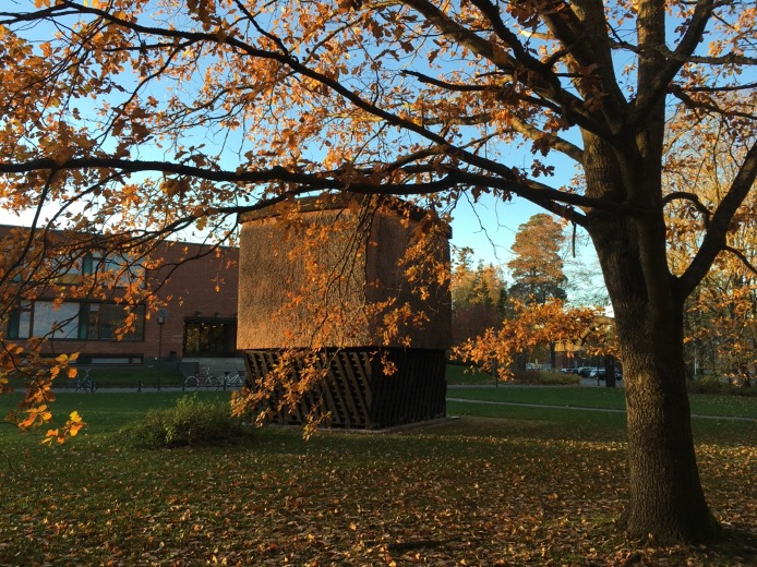 A wooden sculpture on a park seen between autumn trees